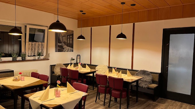 Gemütliches Restaurant mit Holzdecken, Tischen, roten Stühlen und eleganter Dekoration.