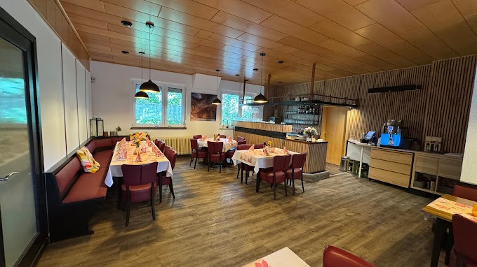 Innenansicht eines gemütlichen Restaurants mit Tischen und Holzverkleidung.