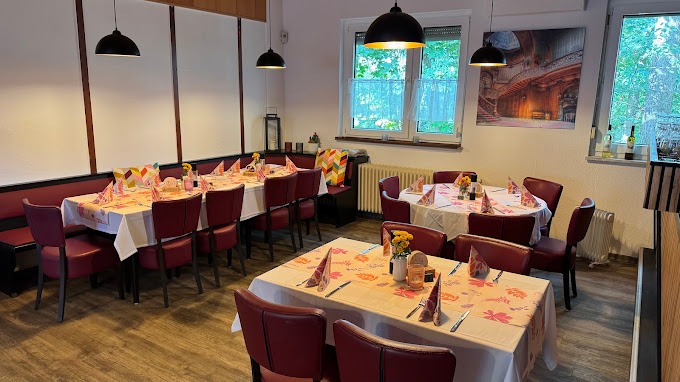 Gemütlich eingerichteter Speisesaal mit gedeckten Tischen und Fenstern.