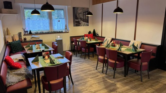 Gemütliches Restaurant mit roten Stühlen, grünem Tischdecken und stimmungsvollem Licht.